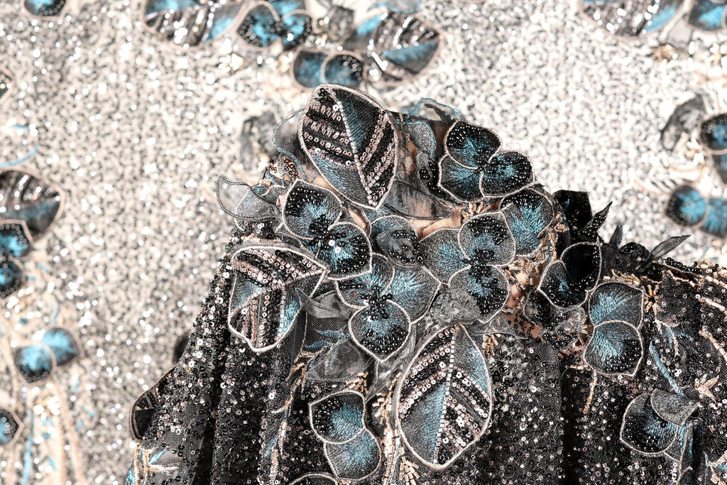 a close-up view of a black and silver sequined dress with a floral pattern.