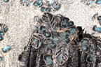 a close-up view of a black and silver sequined dress with a floral pattern.