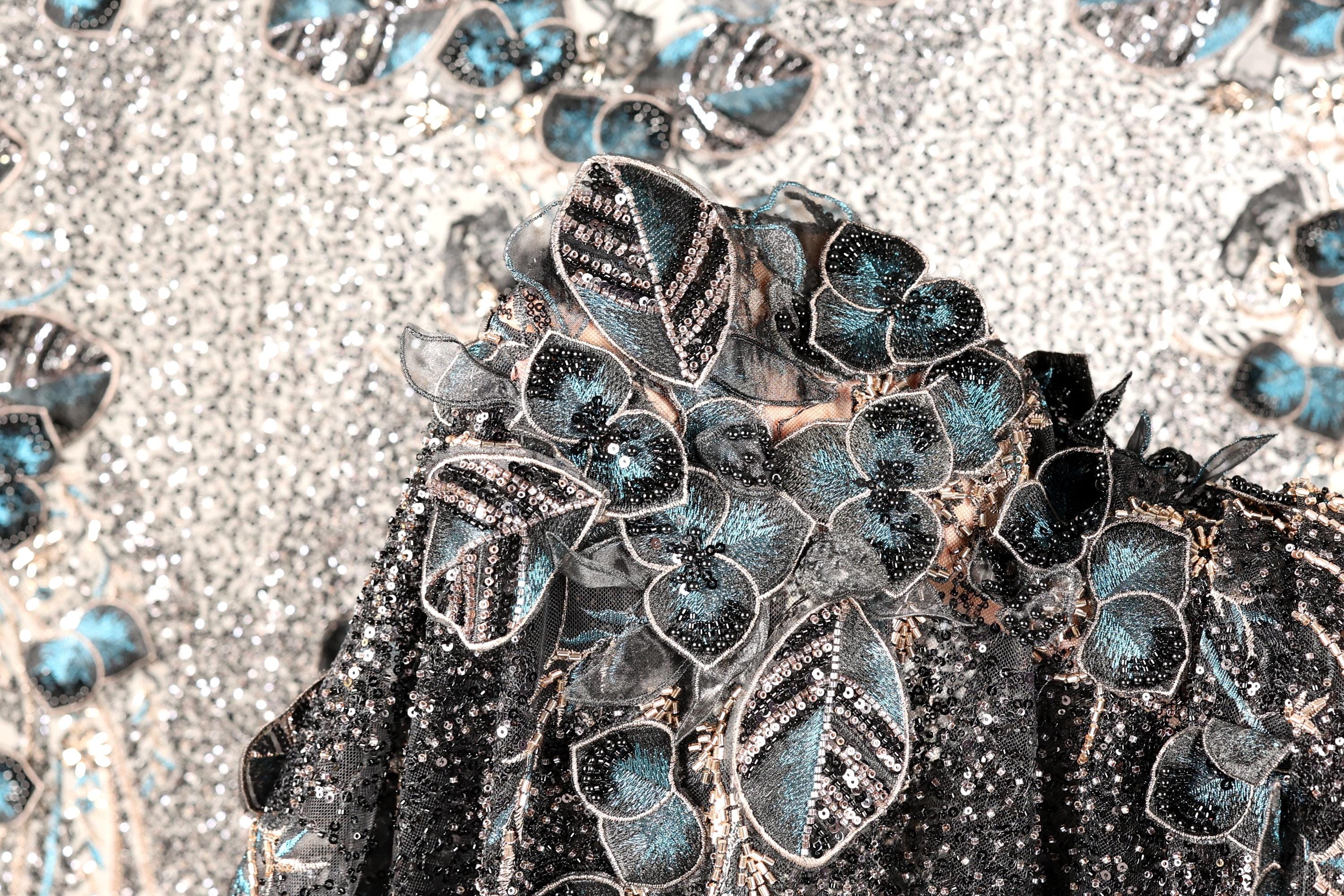 a close-up view of a black and silver sequined dress with a floral pattern.