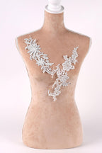 A mannequin wearing a beige dress with a delicate white lace overlay.