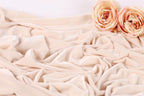 two delicate pink roses resting on a crumpled, light pink fabric.