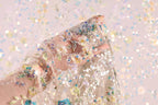 A hand is holding a delicate, intricately embroidered fabric with a floral pattern.