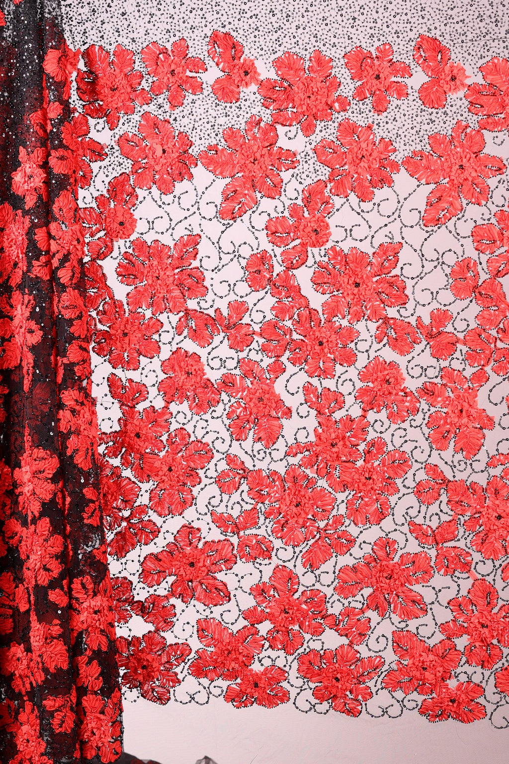 a close-up view of a fabric with a floral pattern in red and black colors. The fabric appears to be made of a sheer material, with a black and red floral design covering the entire surface. The pattern is intricate and detailed, showcasing the craftsmanship of the fabric.