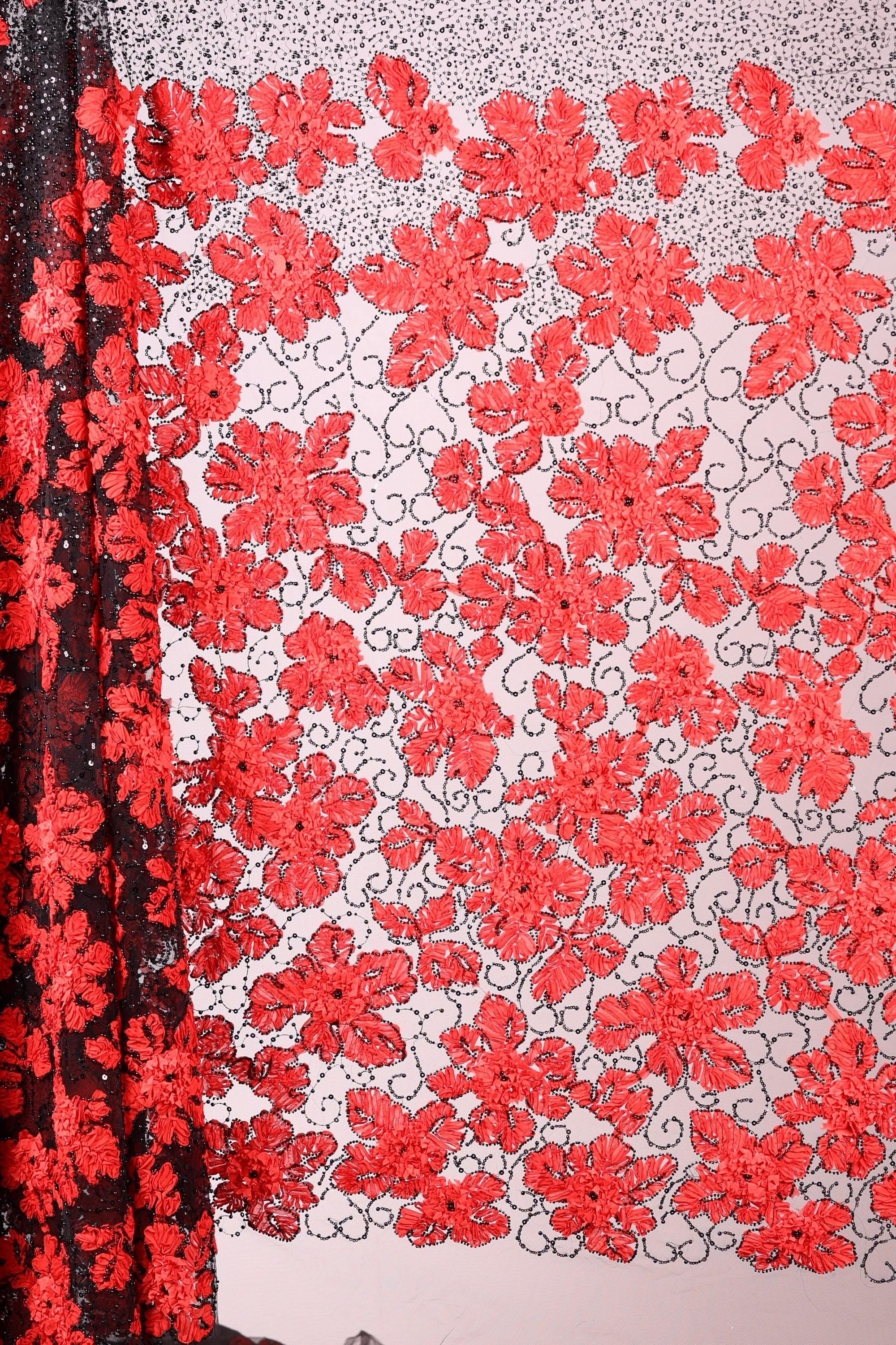 a close-up view of a fabric with a floral pattern in red and black colors. The fabric appears to be made of a sheer material, with a black and red floral design covering the entire surface. The pattern is intricate and detailed, showcasing the craftsmanship of the fabric.