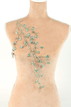 A mannequin torso with a decorative green leaf-like branch on the back.