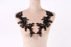 A mannequin wearing a black lace dress with intricate floral patterns.