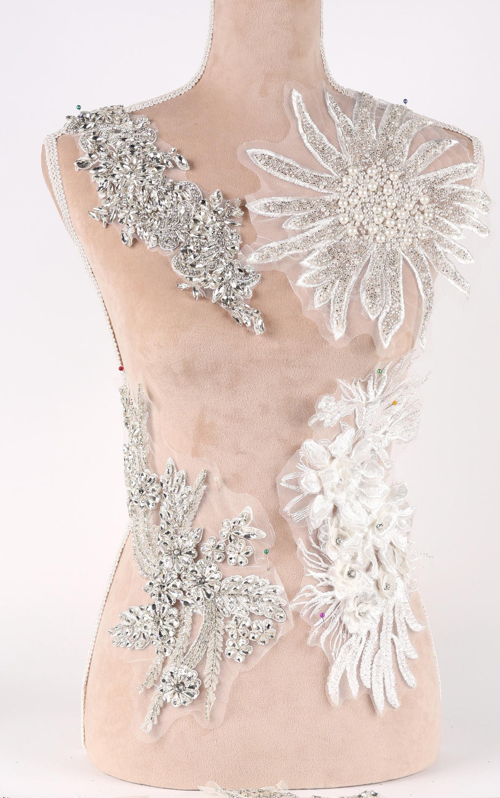 A mannequin torso wearing a dress with various decorative embellishments, including large floral and crystal-like pieces.