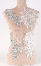 A mannequin torso wearing a dress with various decorative embellishments, including large floral and crystal-like pieces.