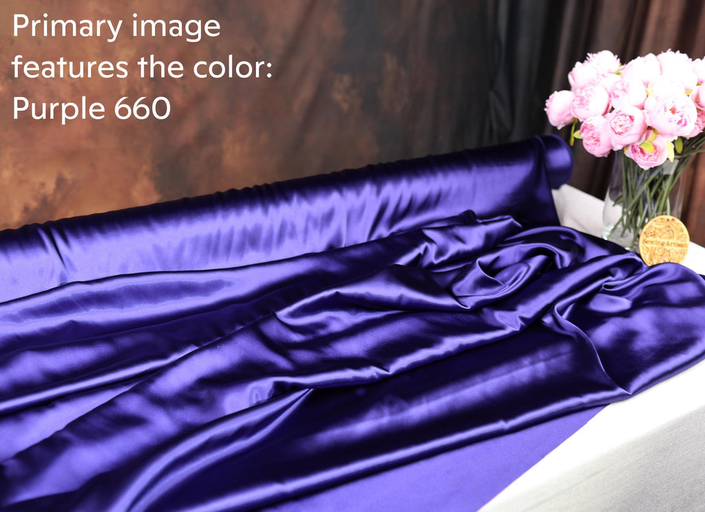 a purple satin fabric with a vase of pink flowers on a table.