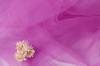 a delicate arrangement of small white flowers resting on a soft, flowing pink fabric.