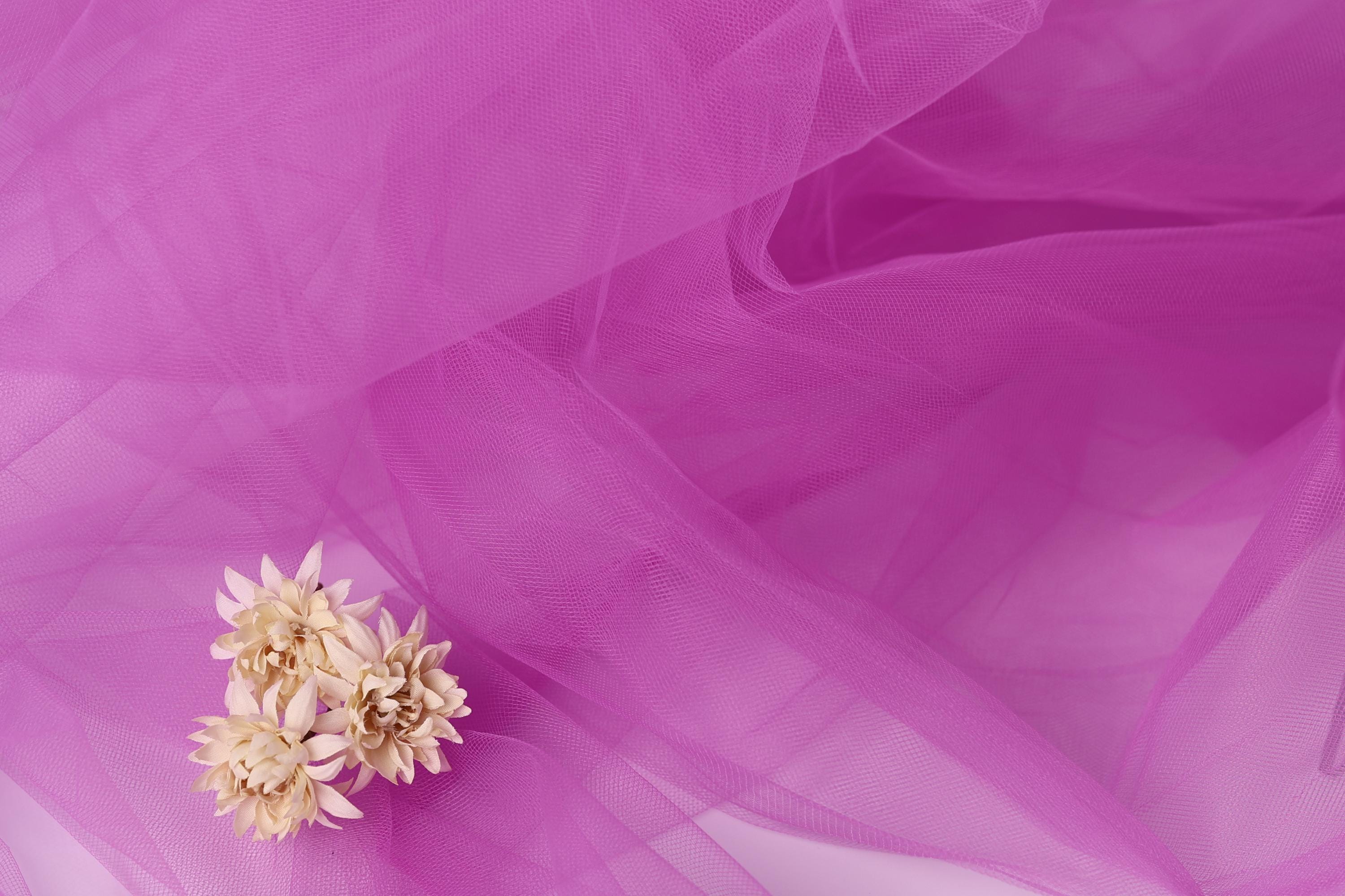 a delicate arrangement of small white flowers resting on a soft, flowing pink fabric.