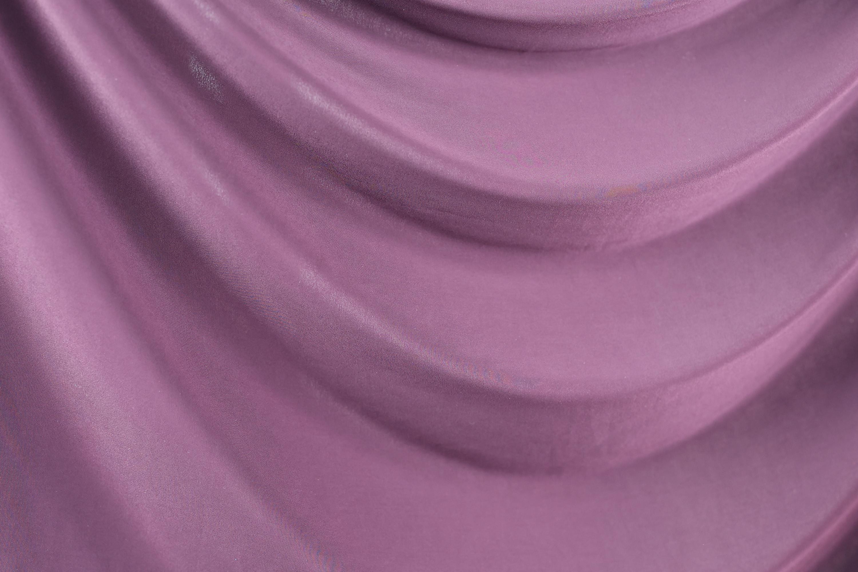 The image is a close-up of a purple fabric with a soft, flowing texture.