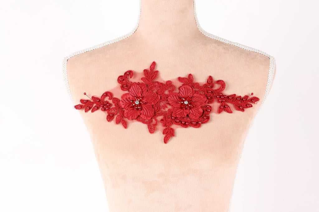 A mannequin torso with red floral embroidery on it.