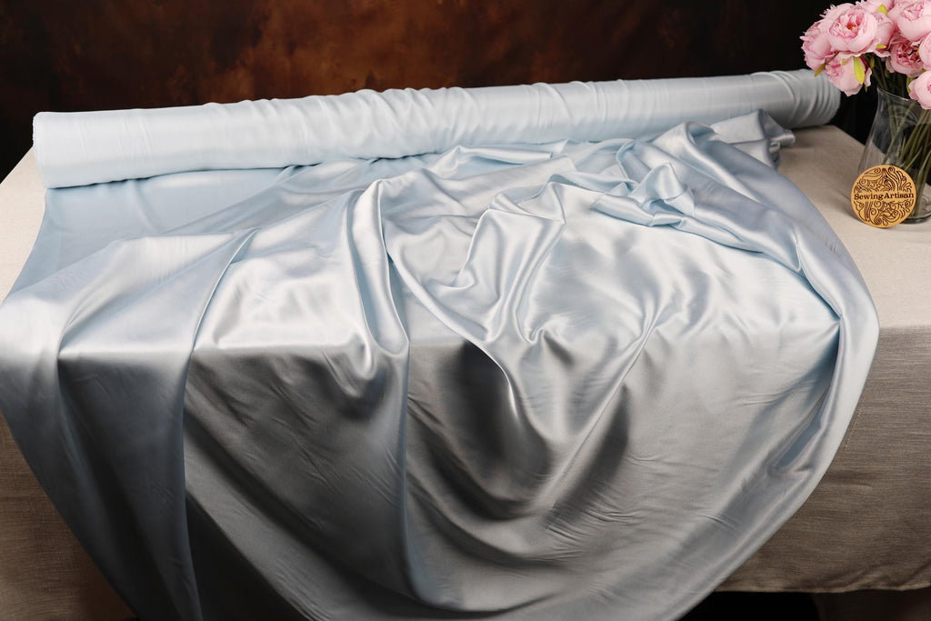 a bed covered with a blue sheet and a vase of flowers