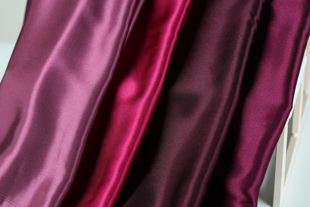 a close-up view of three different colored satin fabrics, with the fabrics appearing to be shiny and smooth.
