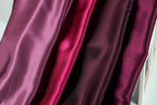 a close-up view of three different colored satin fabrics, with the fabrics appearing to be shiny and smooth.
