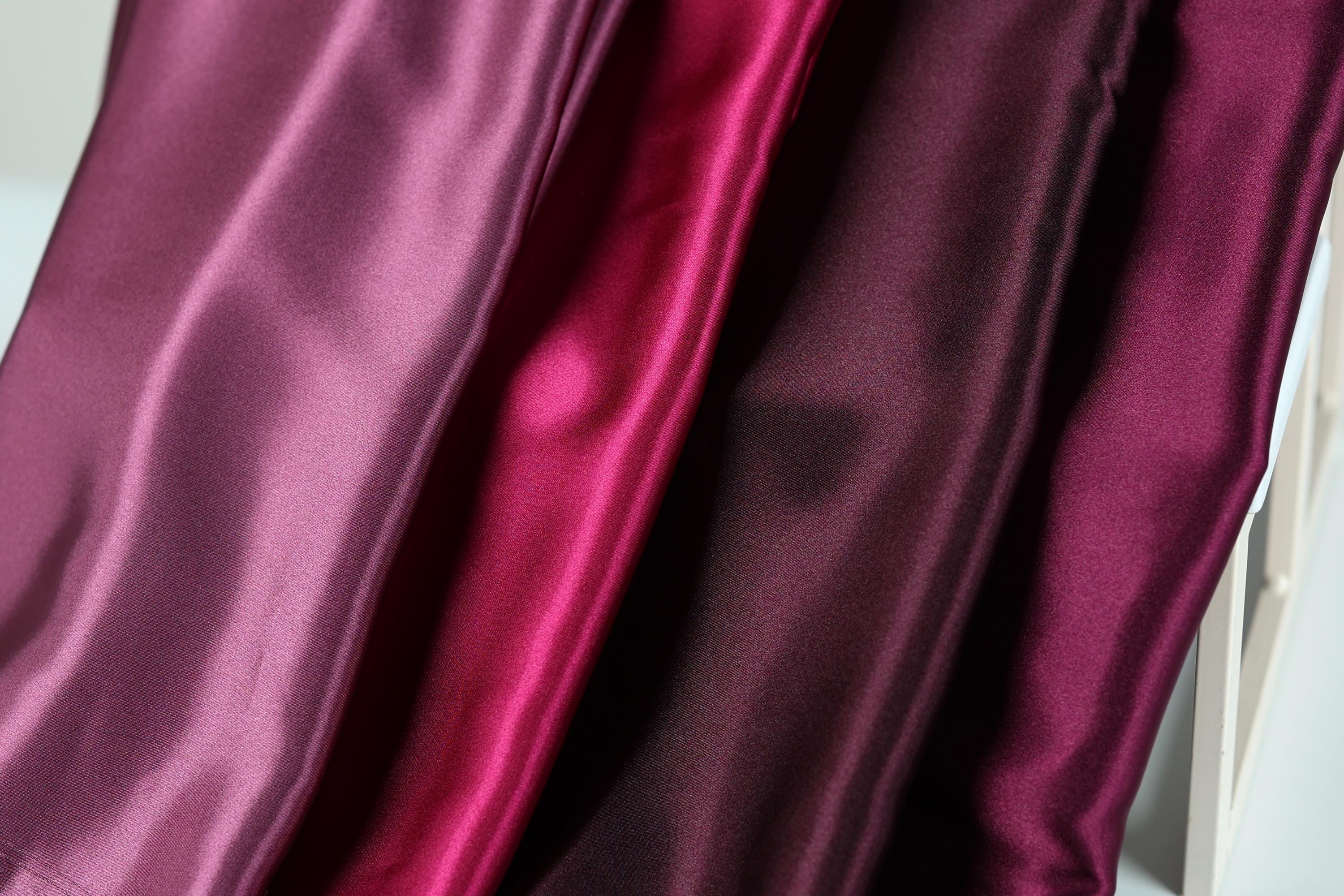 a close-up view of three different colored satin fabrics, with the fabrics appearing to be shiny and smooth.