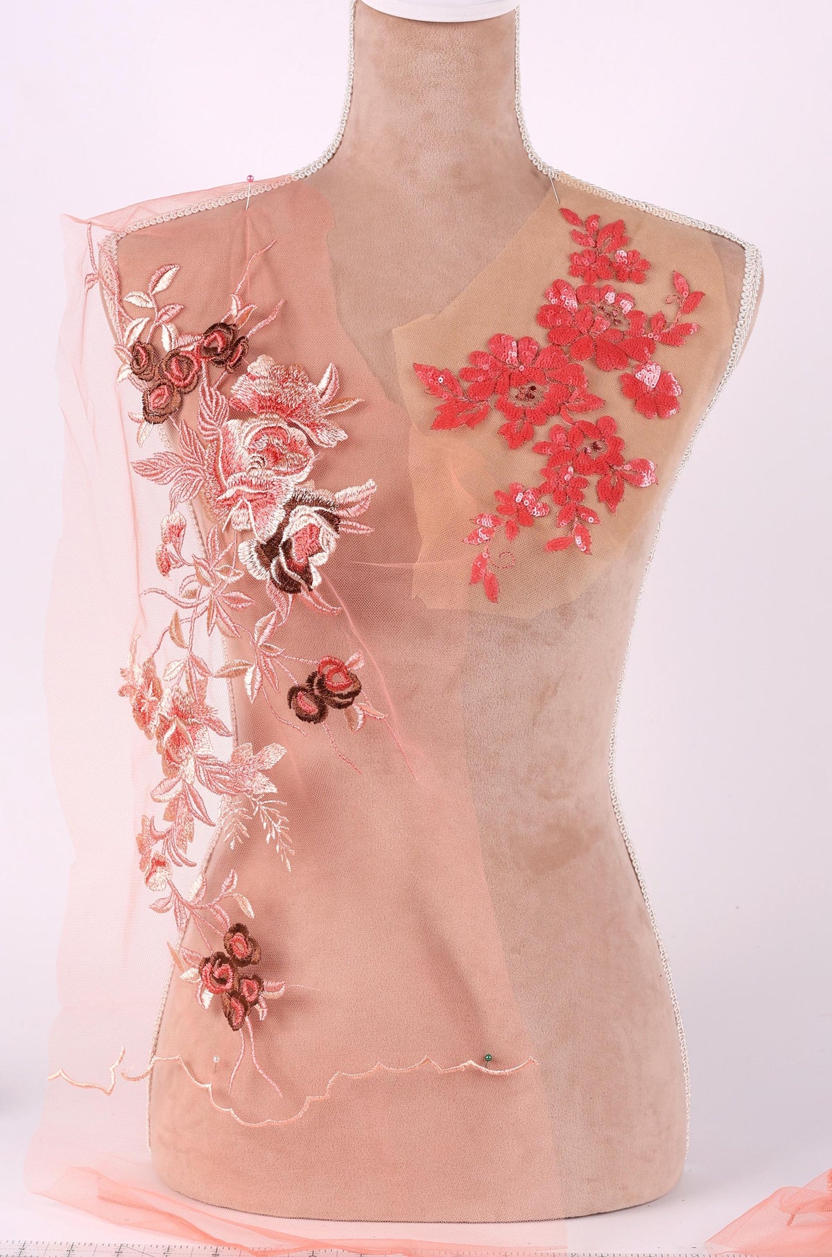 A mannequin wearing a dress with pink and red floral embroidery on the chest area.