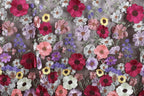 a close-up view of a fabric with a vibrant floral pattern. The fabric is adorned with a variety of colorful flowers, including red, pink, purple, and yellow flowers, as well as green leaves. The flowers are intricately embroidered or stitched onto the fabric, creating a visually striking and detailed design. The image does not contain any text or other discernible objects, and the focus is solely on the floral pattern on the fabric.