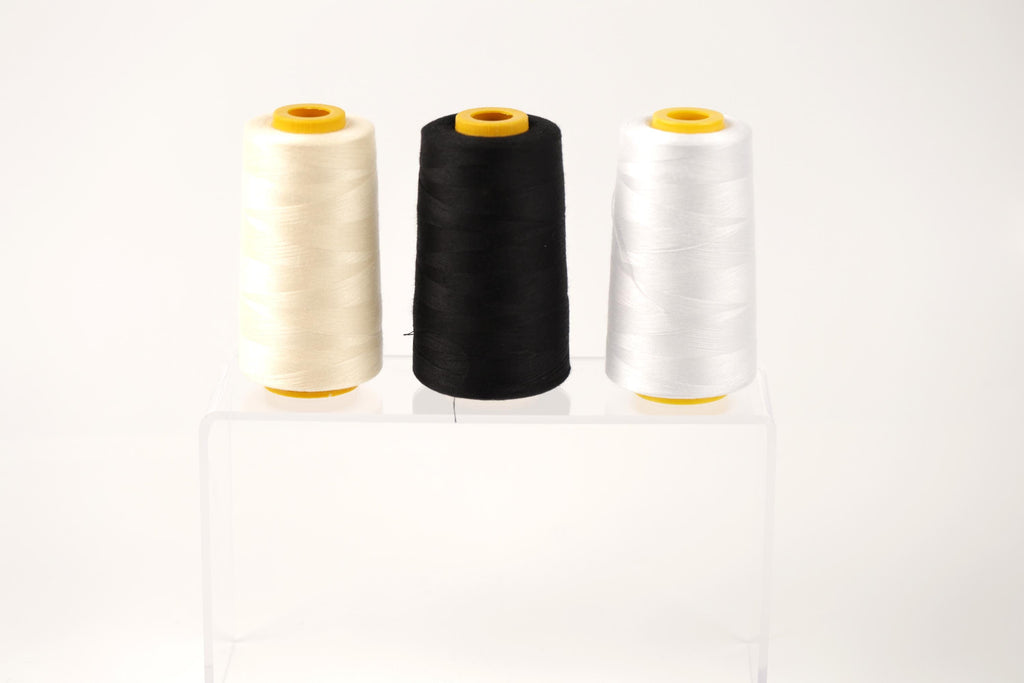 Three spools of thread in different colors - white, black, and beige - are displayed on a clear stand against a white background.