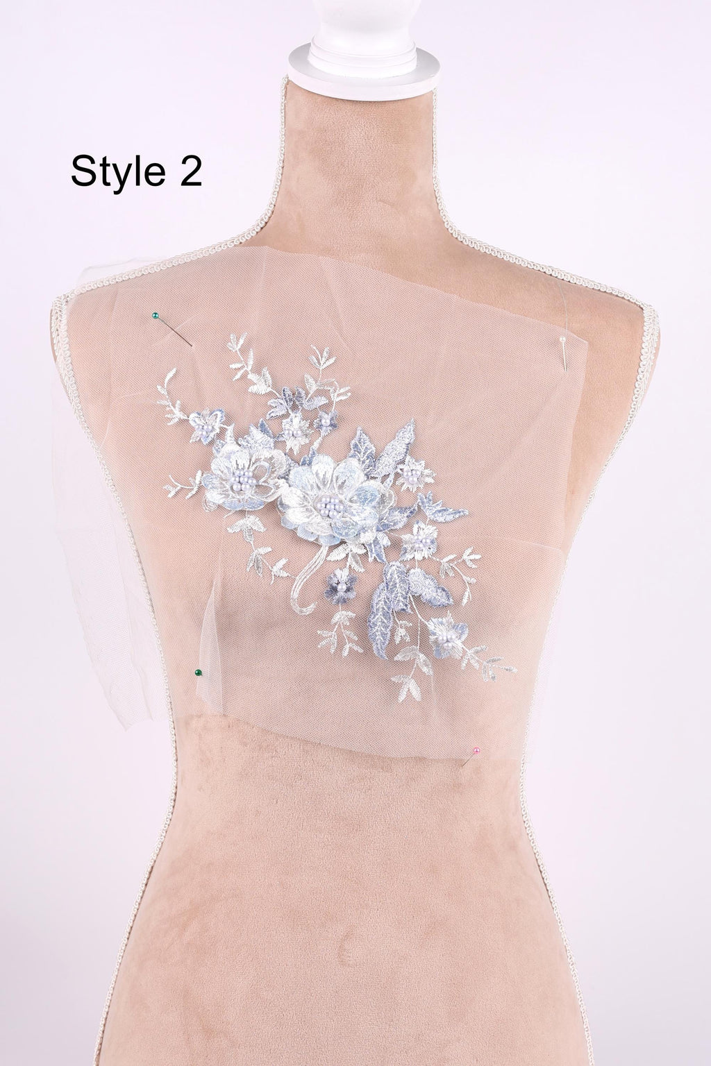 A mannequin wearing a white dress with a floral embroidered design on the back.