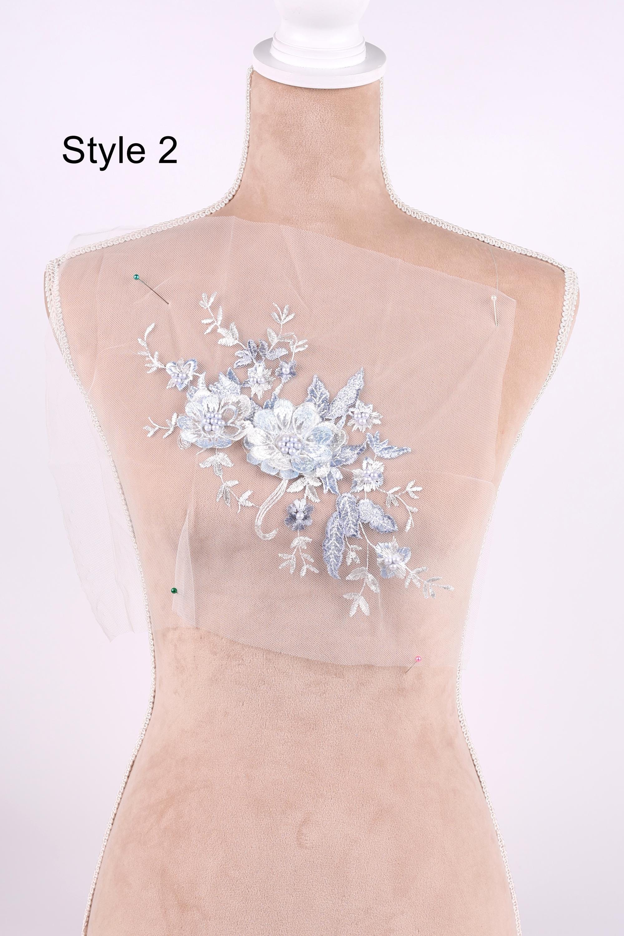 A mannequin wearing a white dress with a floral embroidered design on the back.