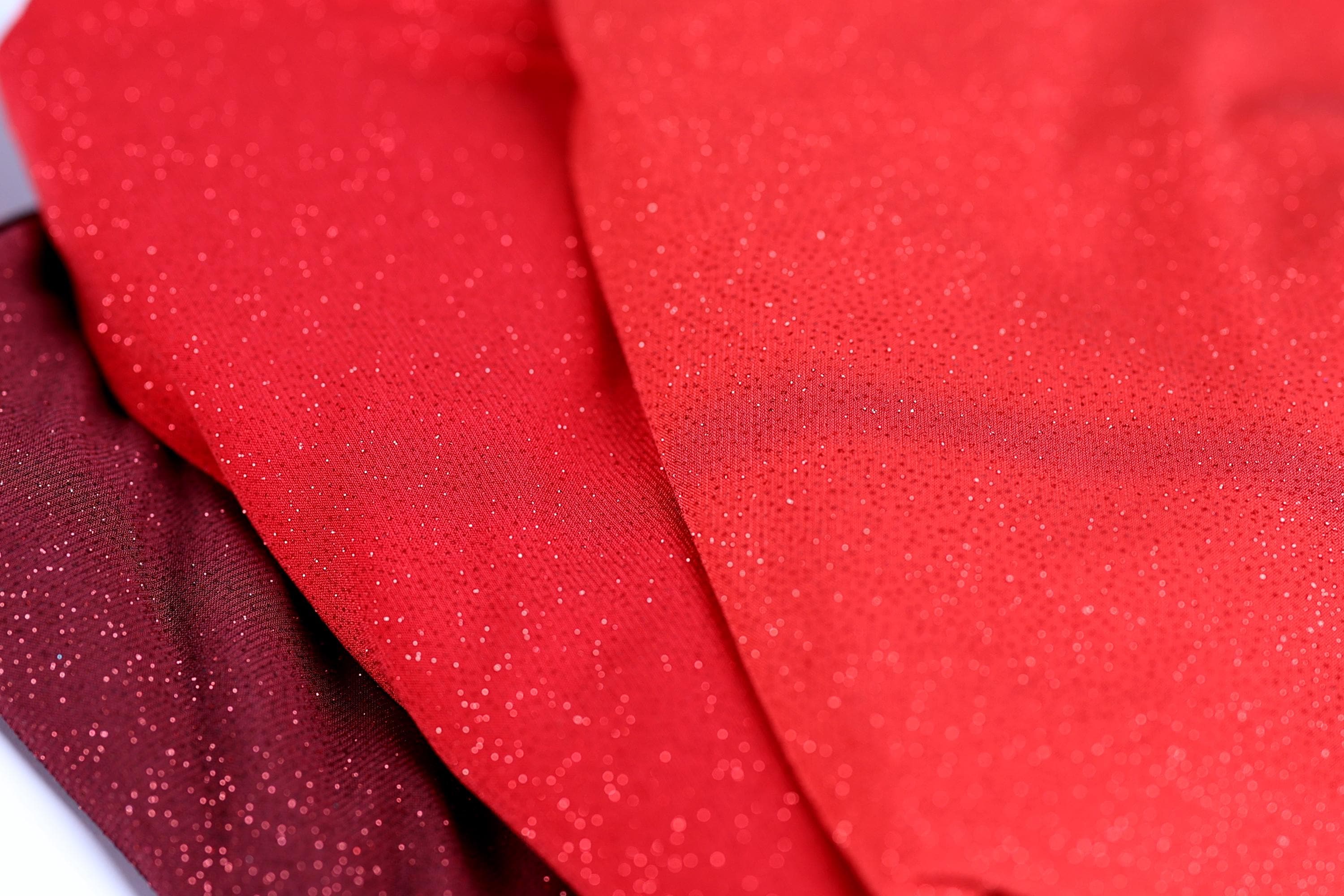 a close-up view of a red fabric with a sparkly texture, creating a visually striking contrast against the background.