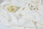 a close-up view of a white fabric with a small yellow flower resting on it.