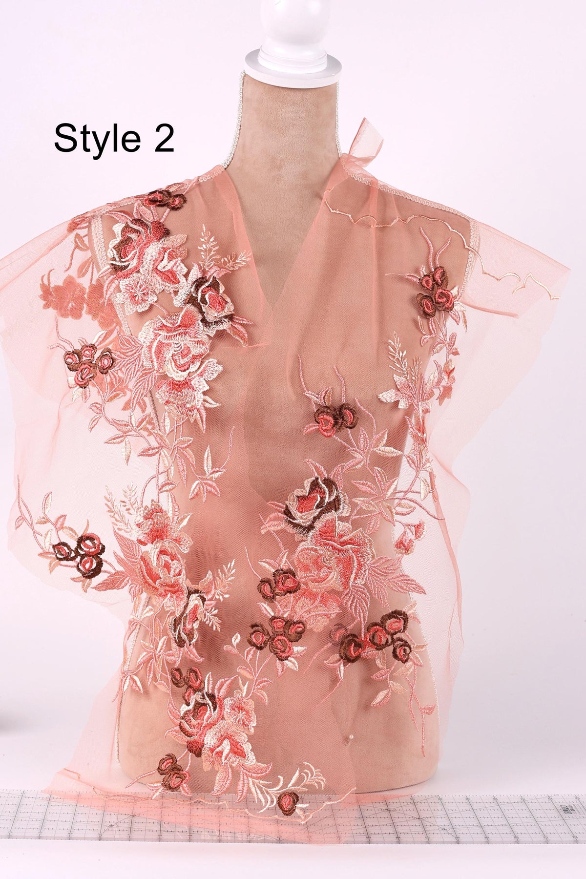 A mannequin wearing a pink floral dress with a sheer overlay, featuring a variety of pink and red floral patterns.