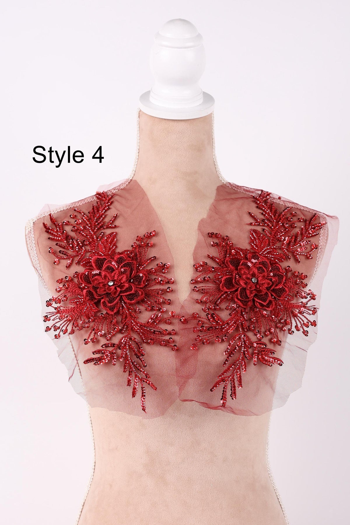 A mannequin wearing a red floral-embellished dress with a white headband.