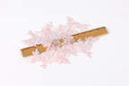 a collection of delicate, pink lace pieces scattered across a wooden ruler, which is placed on a white background.