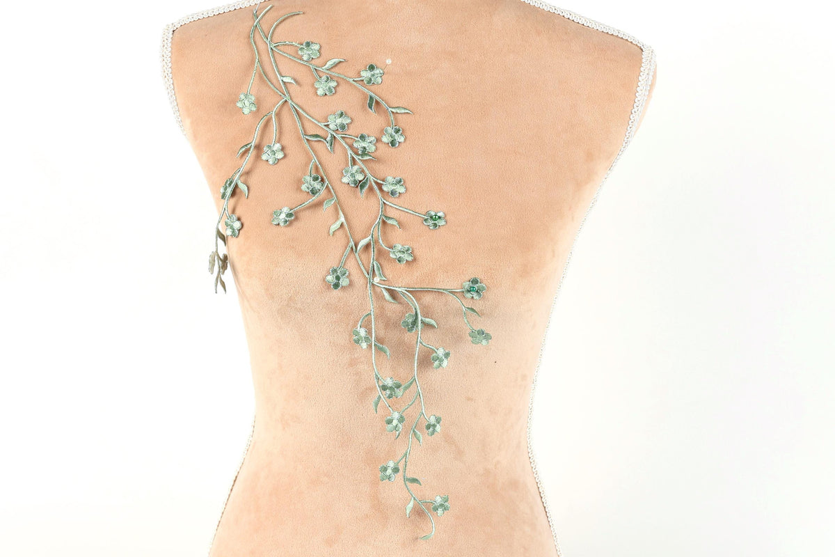 a mannequin torso with a delicate, green floral embroidered on the back.