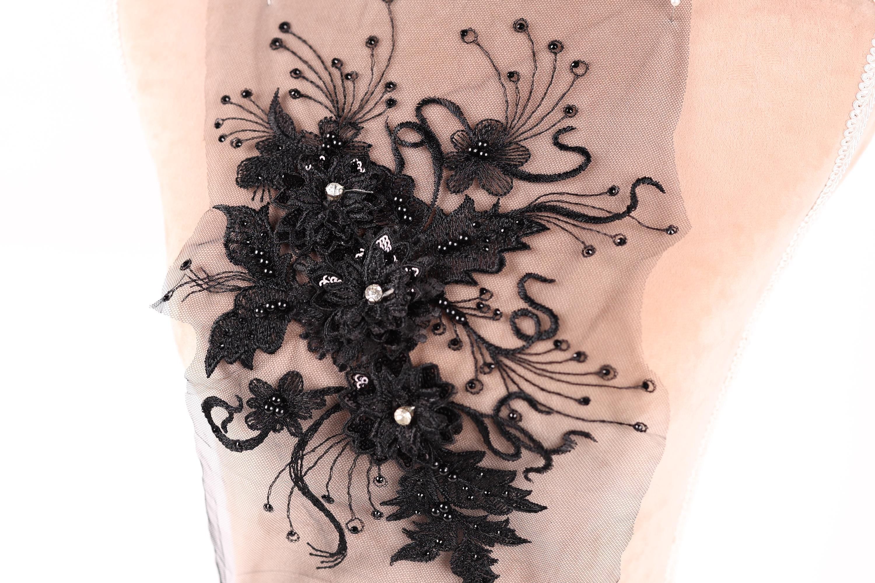 a close-up view of a delicate black lace flower embroidery on a fabric.