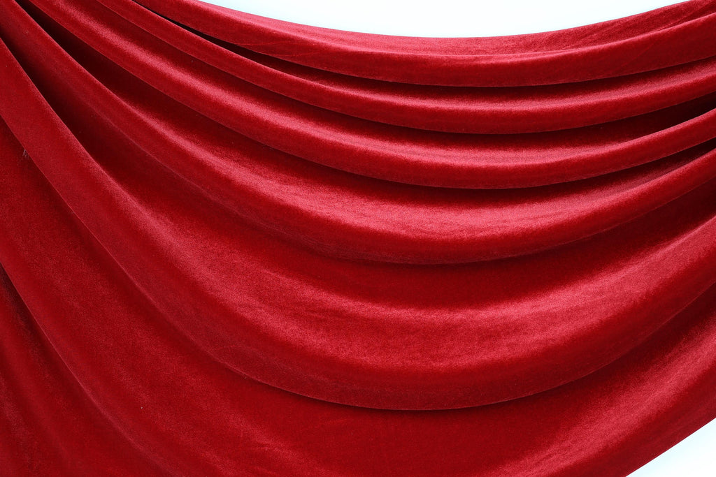 a close-up view of a red velvet fabric, with its folds and creases creating a textured and flowing appearance.