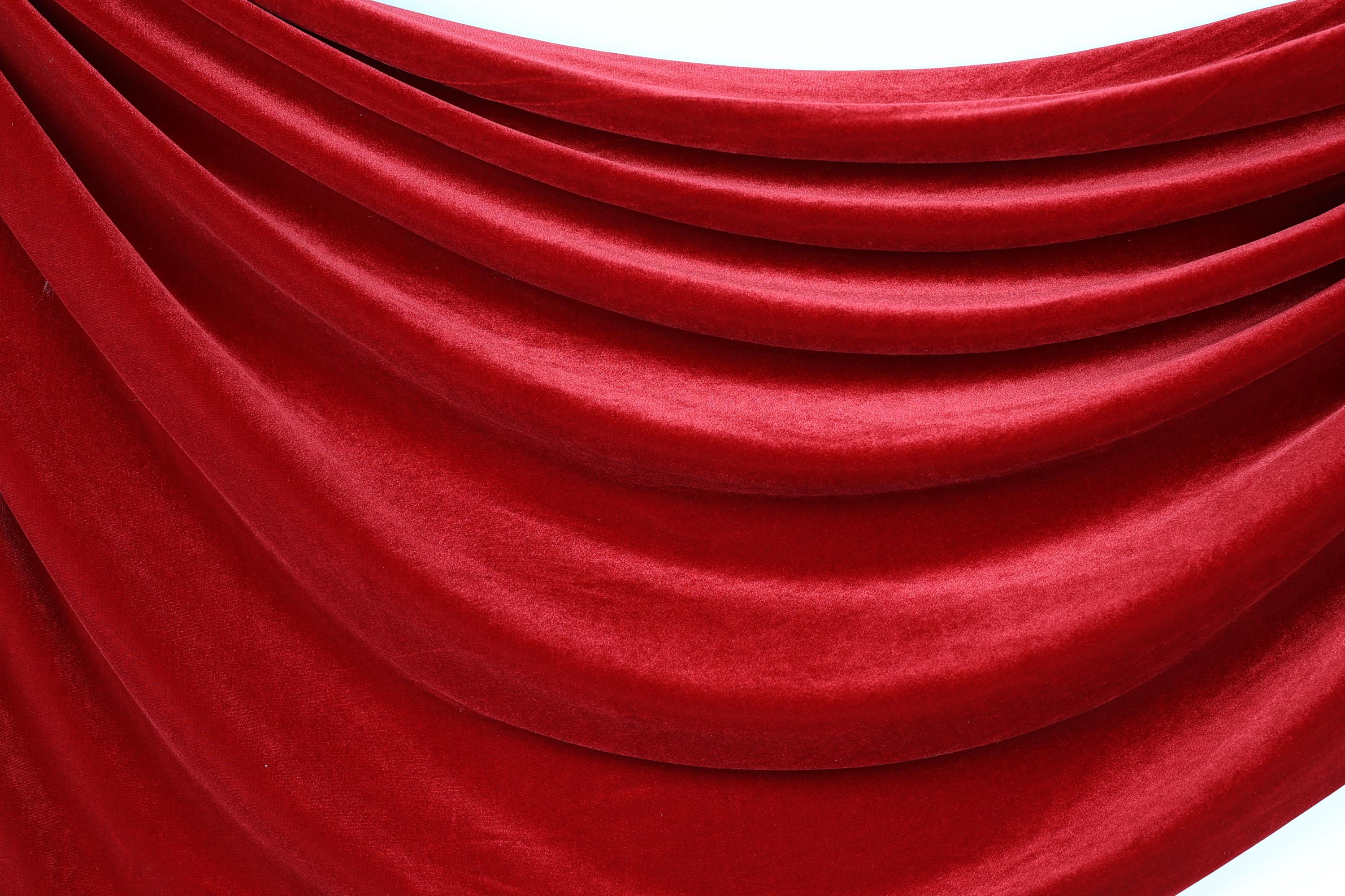 a close-up view of a red velvet fabric, with its folds and creases creating a textured and flowing appearance.