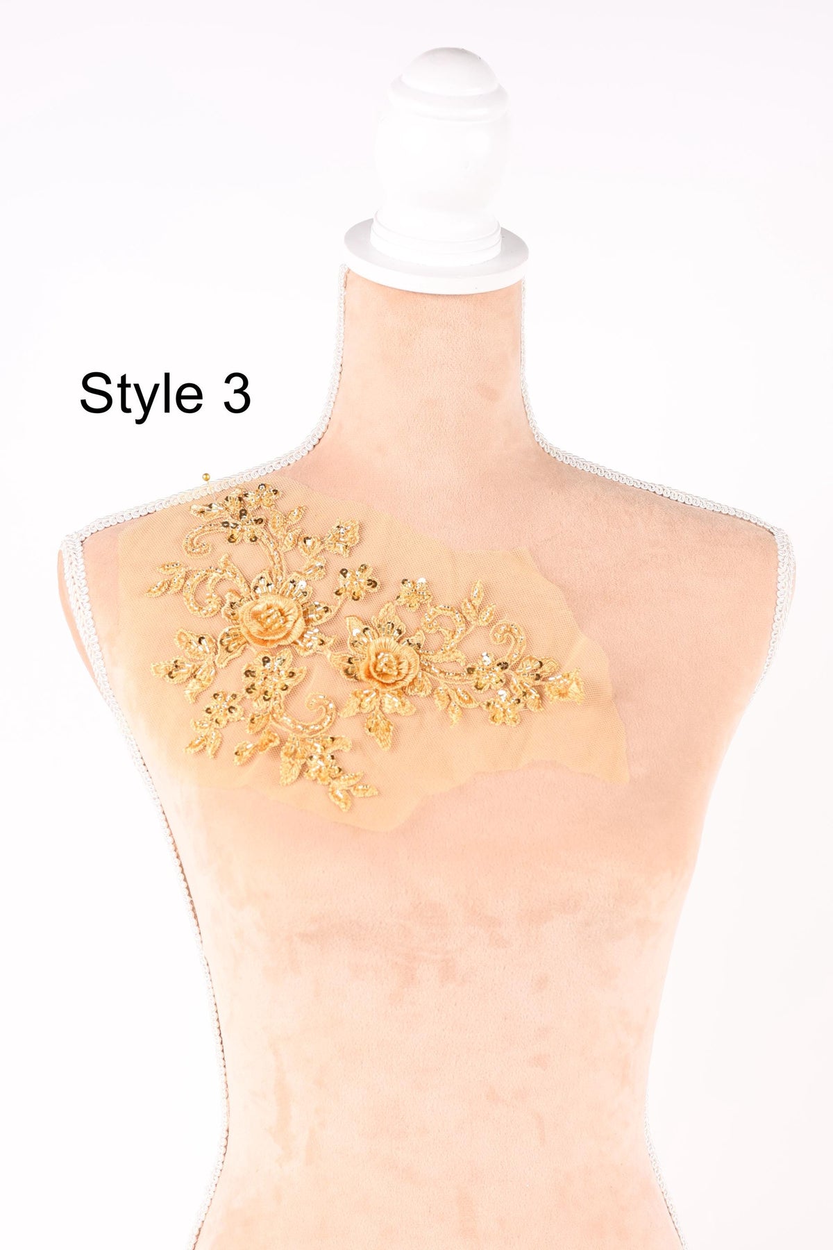 A mannequin with a decorative gold floral embroidery on its chest.
