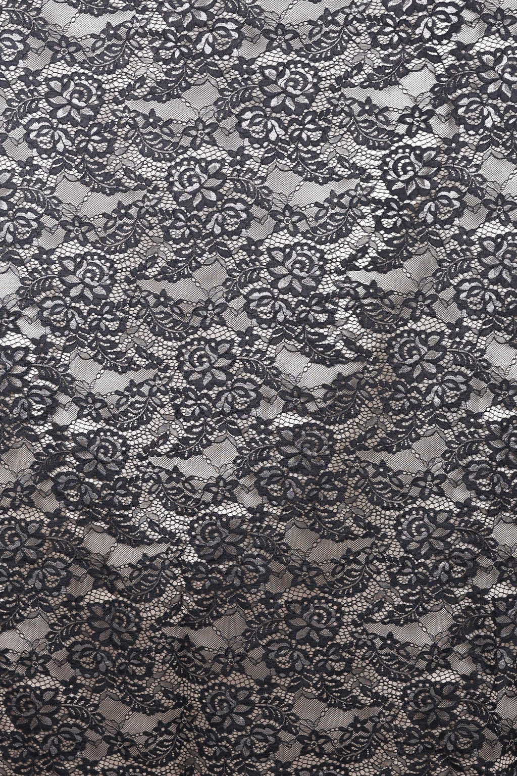 The image is a close-up view of a black and white lace pattern, featuring intricate floral and leaf designs. The lace appears to be a decorative textile, possibly used for clothing or home decor.