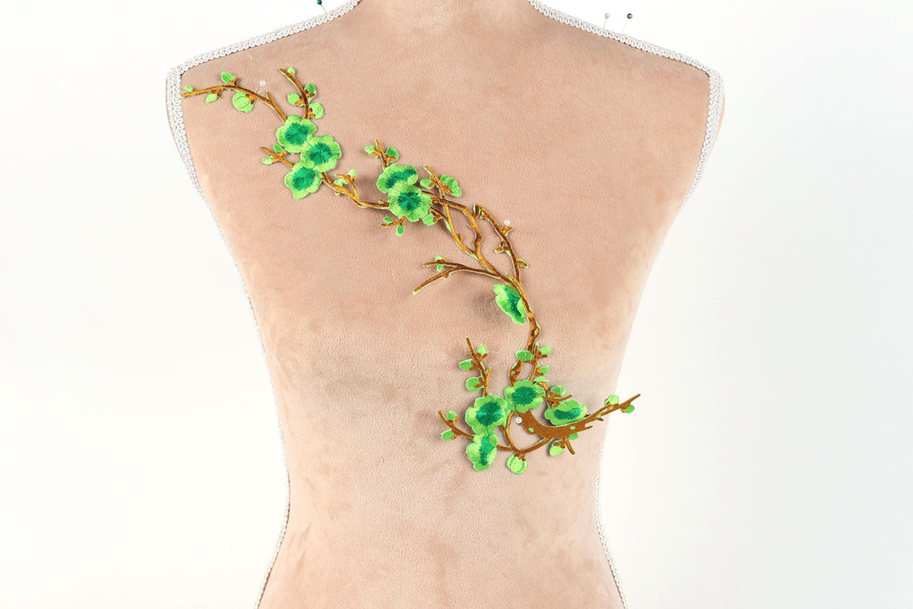 a mannequin with a decorative green leaf and branch embroidered on its back.