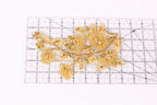 a decorative piece with gold-colored flowers and leaves, placed on a ruler for scale.