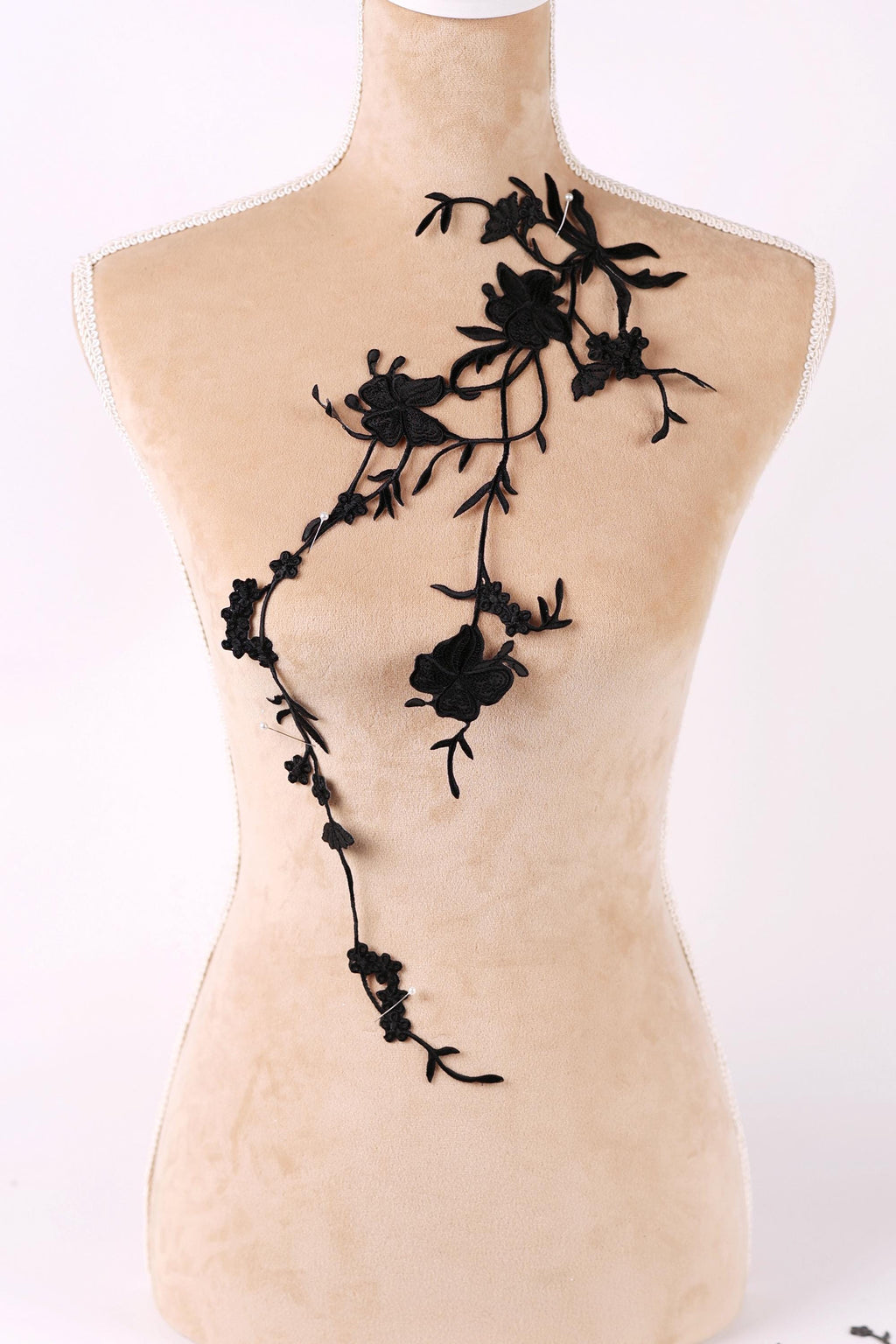 A mannequin torso with a black floral embroidered on it.