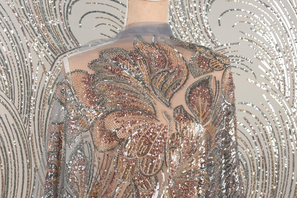 a mannequin wearing a dress with a sheer, sequined bodice. The dress has a floral pattern and appears to be made of a shiny, metallic fabric.