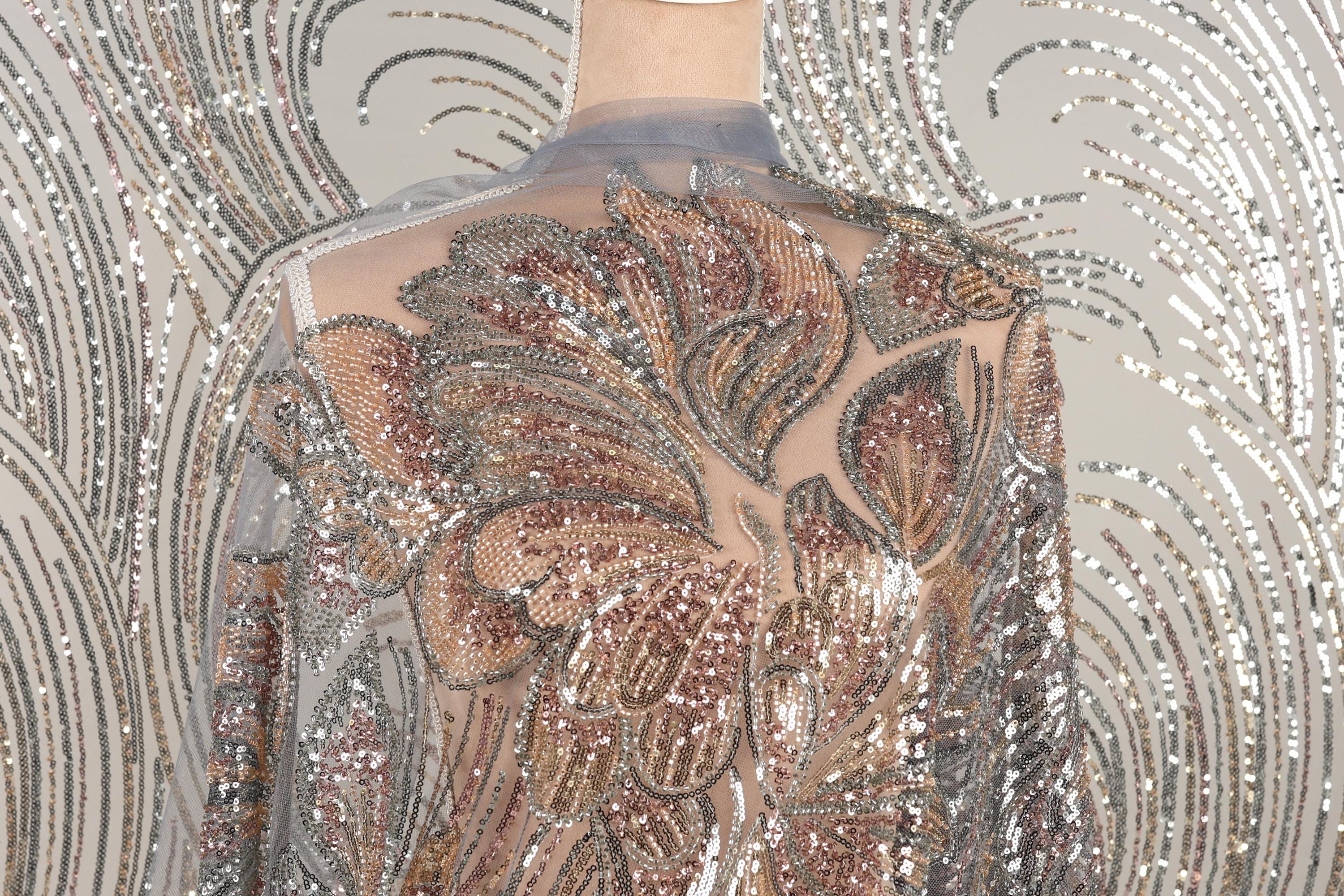 a mannequin wearing a dress with a sheer, sequined bodice. The dress has a floral pattern and appears to be made of a shiny, metallic fabric.