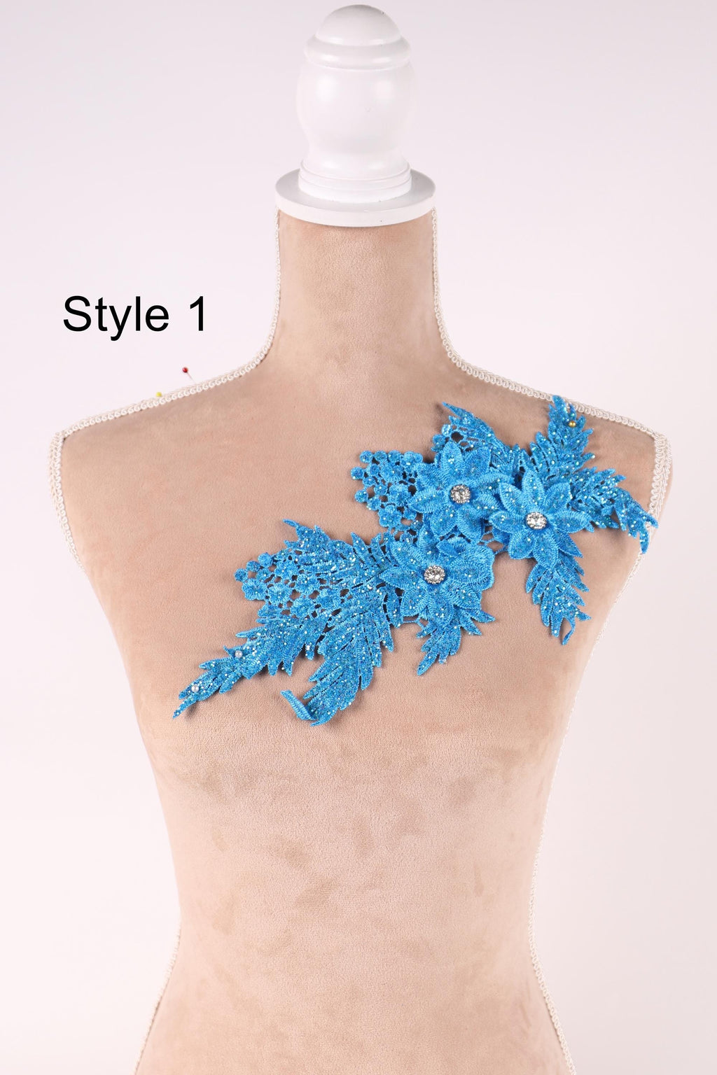 A mannequin with a decorative blue lace piece on its shoulder.