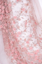 a close-up view of a delicate, pink floral fabric with numerous small pink roses and leaves. The fabric appears to be made of sheer material, giving it a soft and delicate appearance. The roses and leaves are arranged in a way that creates a visually appealing and intricate pattern.