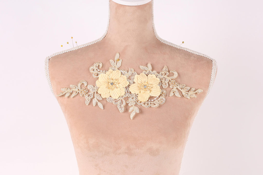 A mannequin with a decorative floral piece on its bust, featuring two yellow flowers and leaves.