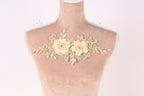 A mannequin with a decorative floral piece on its bust, featuring two yellow flowers and leaves.