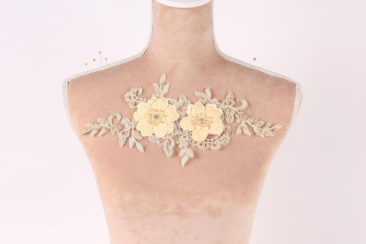 A mannequin with a decorative floral piece on its bust, featuring two yellow flowers and leaves.