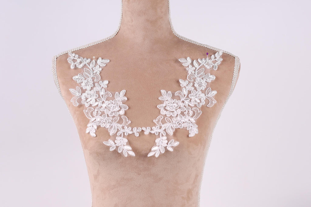 A mannequin with a white lace collar and floral embellishments on the bust area.