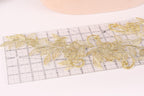 a close-up view of a clear ruler with gold embroidered flowers placed on it.