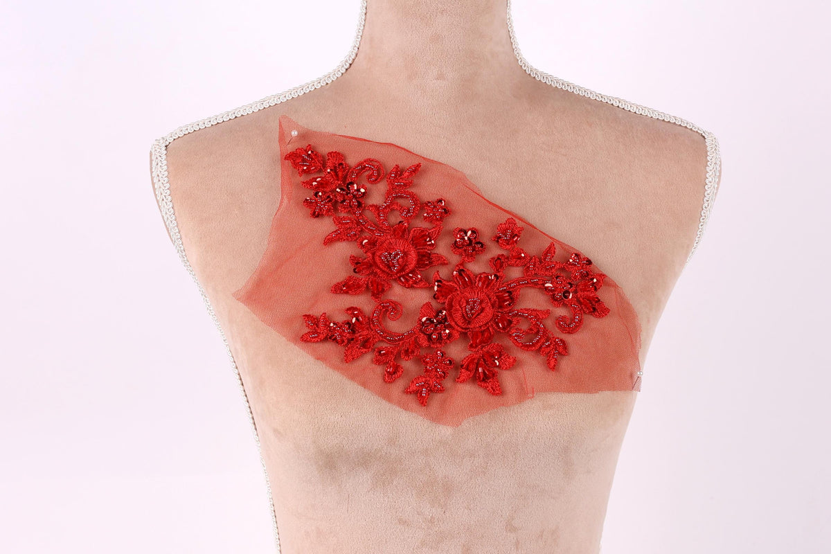 A mannequin torso with a red floral embroidered patch on it.